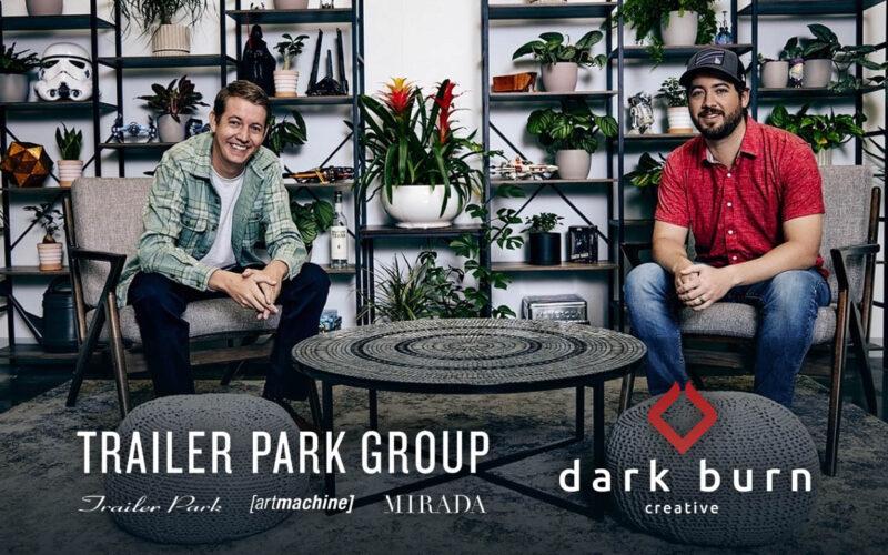 Tanner and Chase Boyajian smiling for the camera at their office with company logos