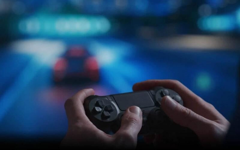 A gamer using a controller with the image of a racing game blurred in the background