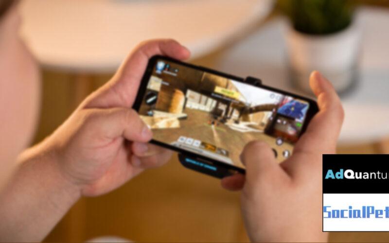A blurred image of a person playing mobile games next to AdQuantum and Social Peta logos