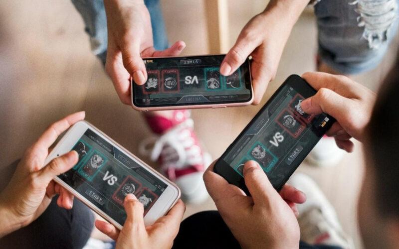 Three people playing an online multiplayer mobile game on smartphones