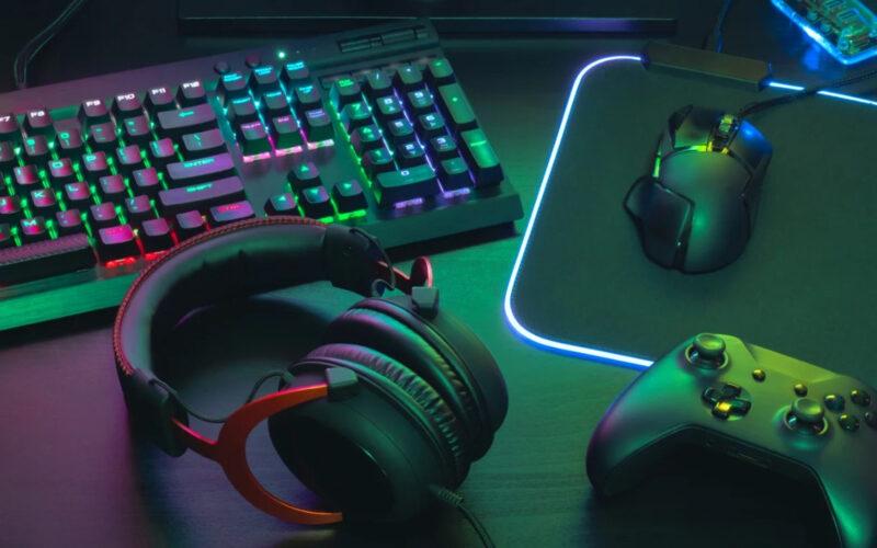 A keyboard, headset, controller, and mouse on a black table