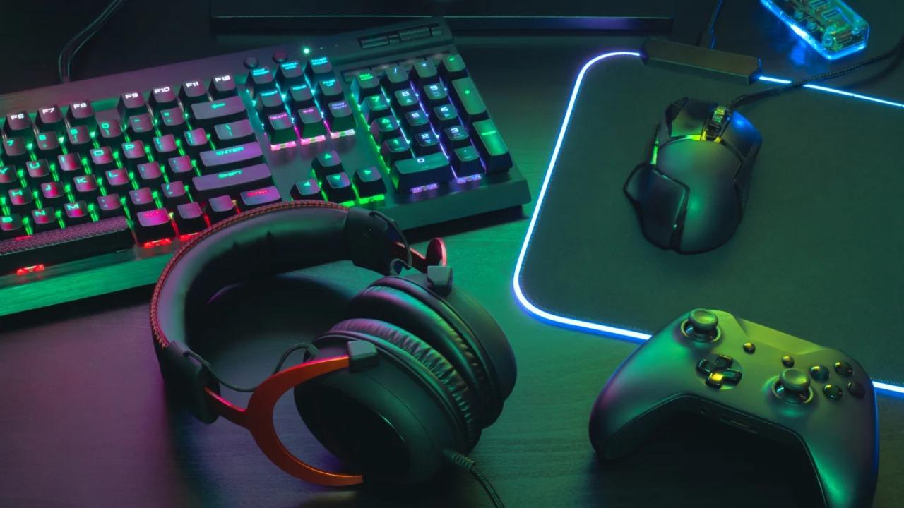 A keyboard, headset, controller, and mouse on a black table