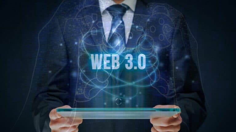 elinde akıllı cihaz tutan takım elbiseli bir kişi ve önünde web 3.0 yazısı.