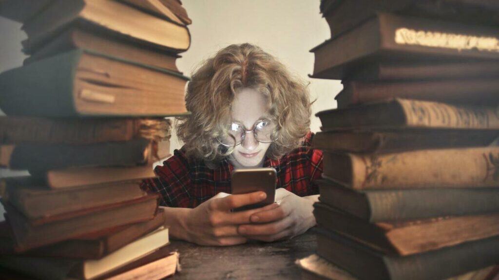 man playing with mobile phone instead of reading books