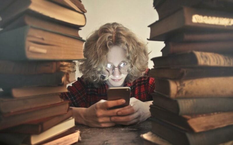 man playing with mobile phone instead of reading books