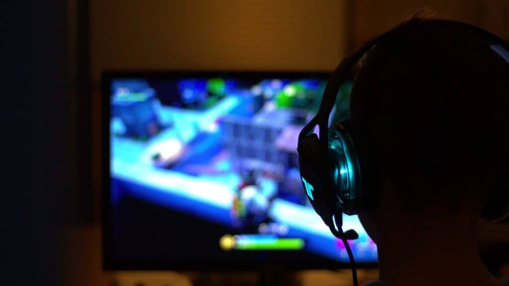 a smart tv with a game on its screen and a man with a headset seen from behind