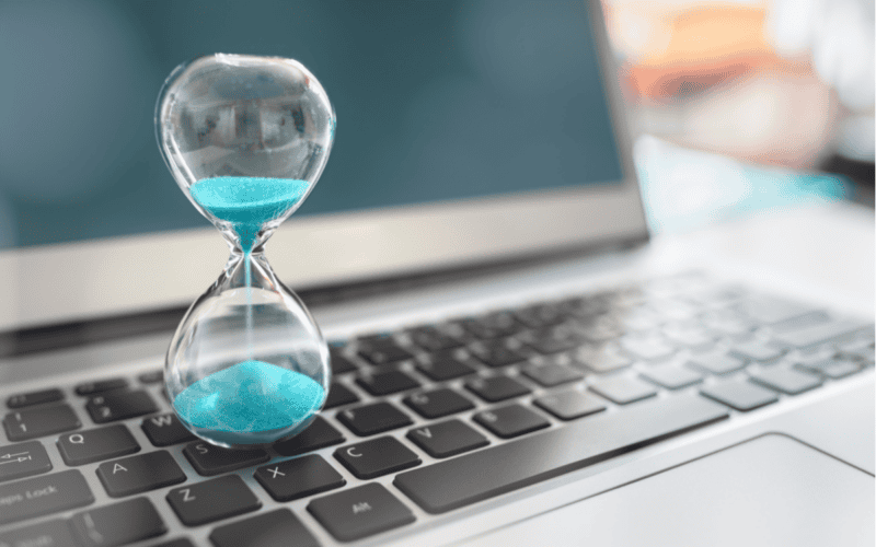 a hourglass sitting on top of a lapto pfor the payback period matters article by deniz kekeç