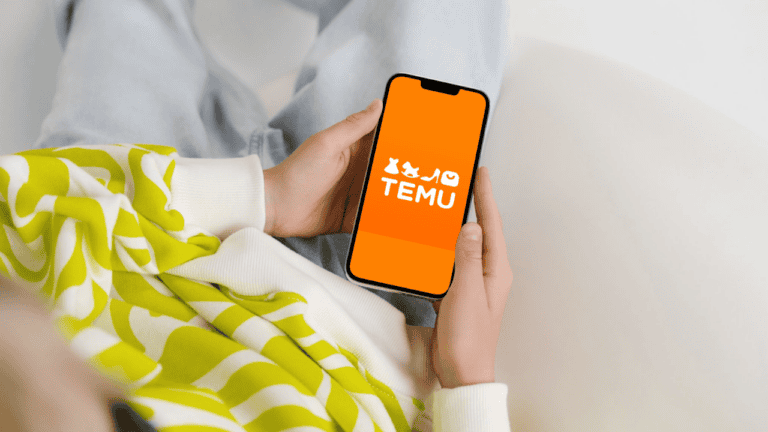 A person holding a smartphone displaying the Temu app logo, representing the top global mobile app market trends for May 2026.